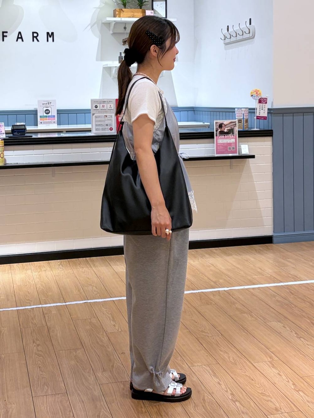 グレー系のスウェットパンツ、ブルー系のキャミソール、ブラック系のショルダーバッグを着用したレディースの夏コーディネートの2枚目の写真