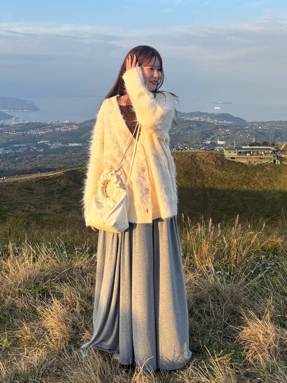 グレー系のスカート、ブラウン系のニット/セーター、ホワイト系のカーディガン/ボレロを着用したレディースの秋コーディネートの3枚目の写真