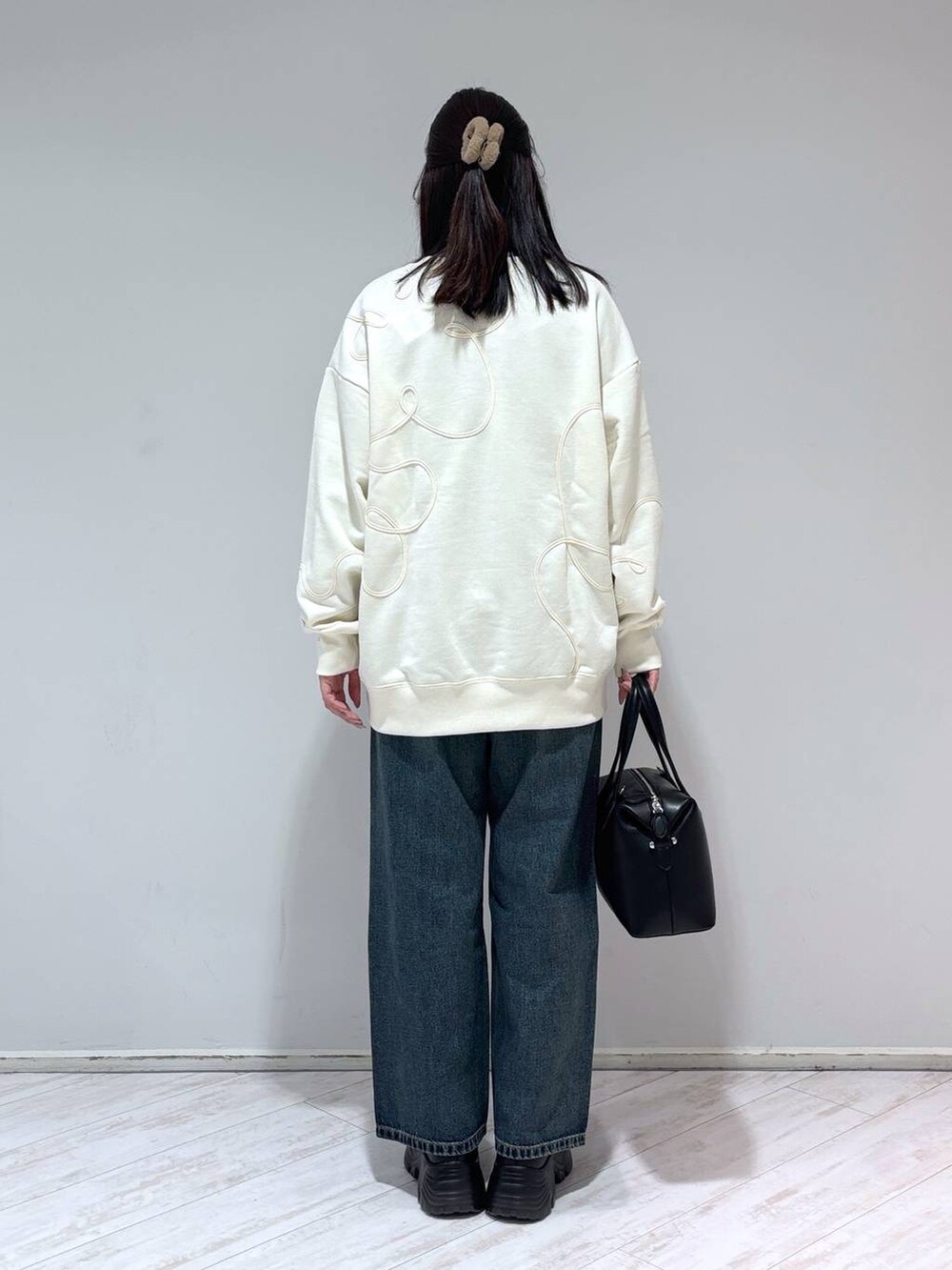 ブラック系のブーツ、ブルー系のデニムパンツ、ブラック系のショルダーバッグを着用したレディースの冬コーディネートの3枚目の写真