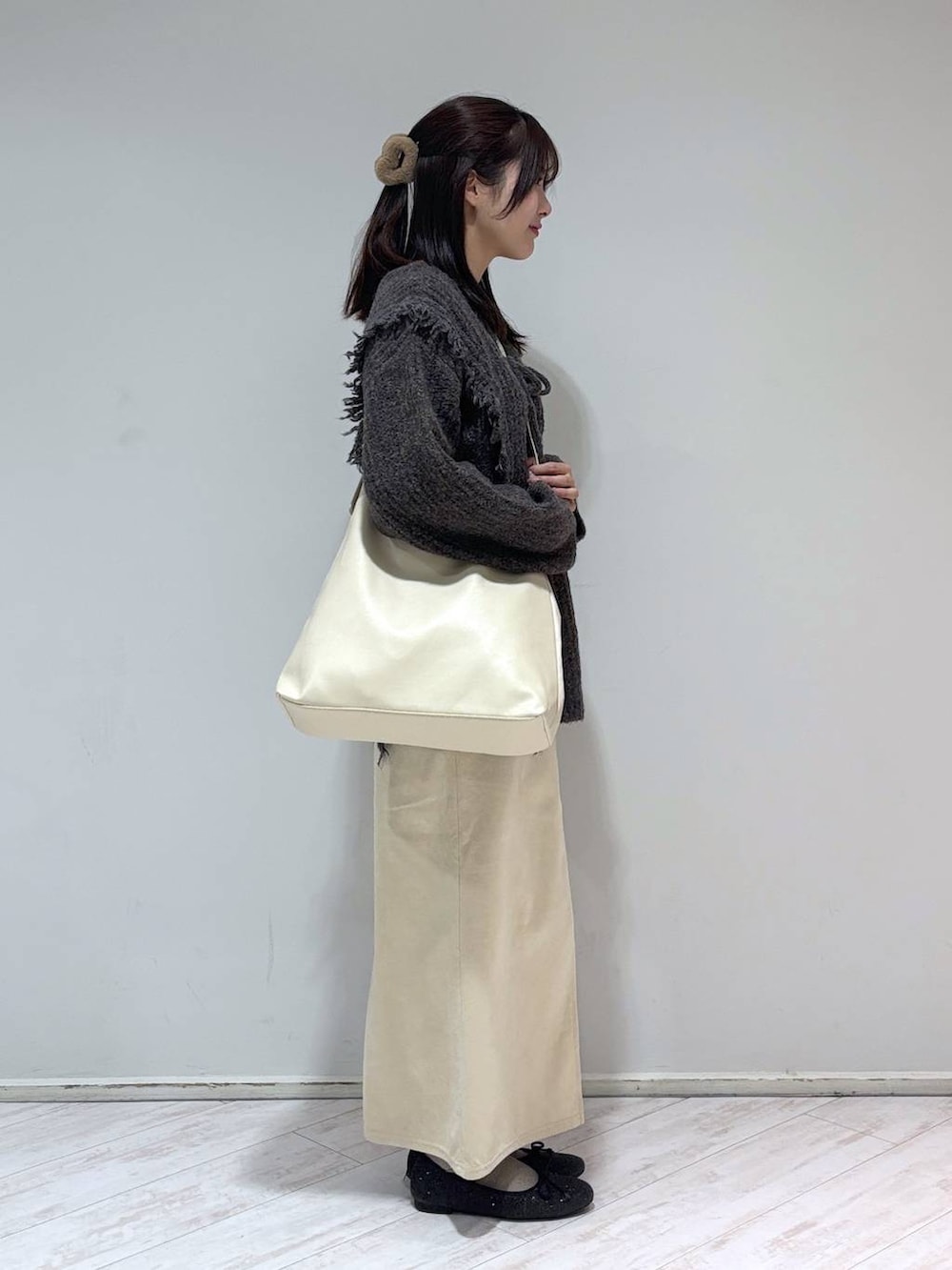 ホワイト系のショルダーバッグ、シルバー系のTシャツ/カットソー、グレー系のニット/セーターを着用したレディースの冬コーディネートの2枚目の写真