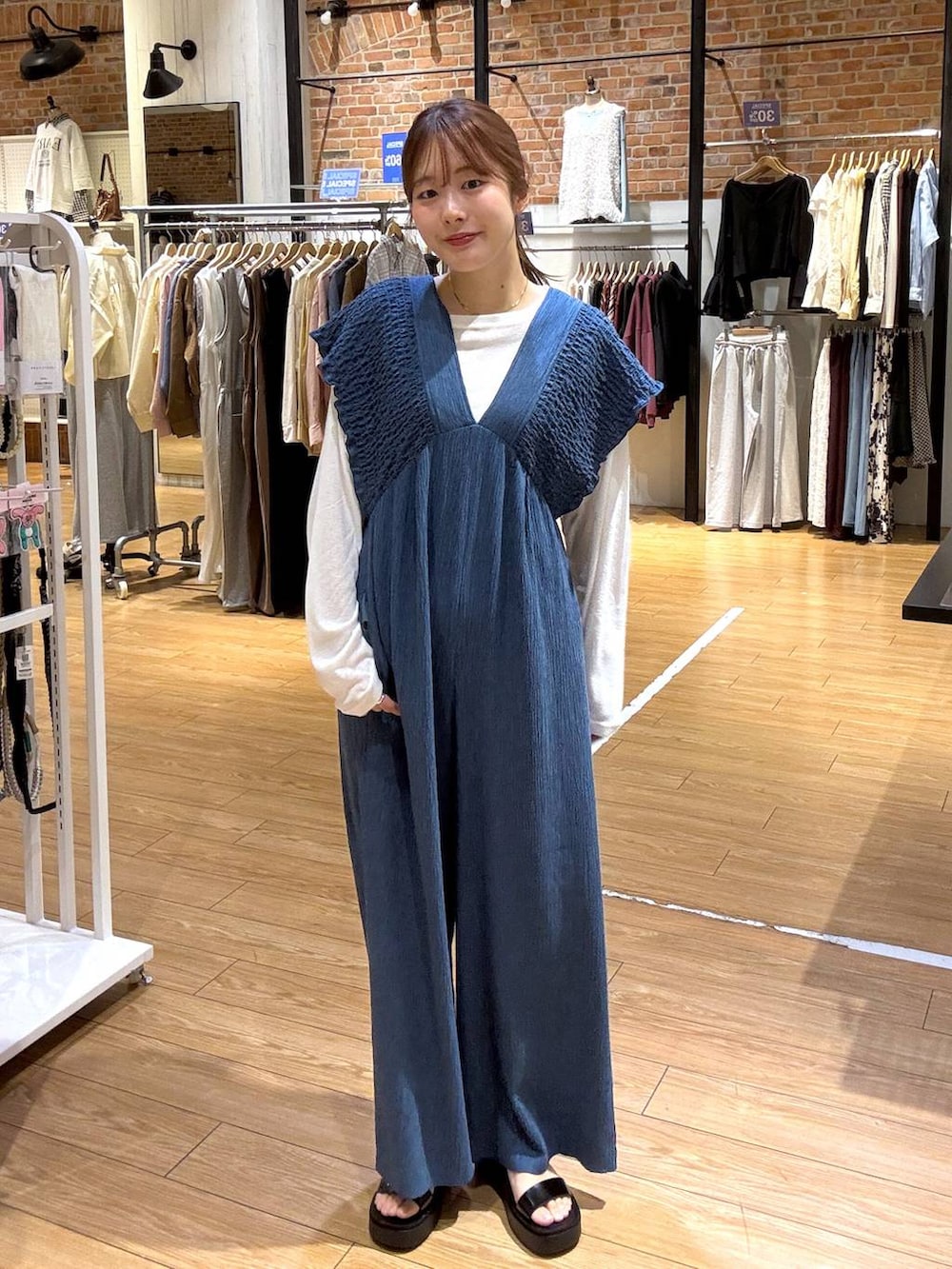 ブルー系のサロペット/オーバーオール、ホワイト系のTシャツ/カットソー、ブラック系のサンダルを着用したレディースの春コーディネートの2枚目の写真