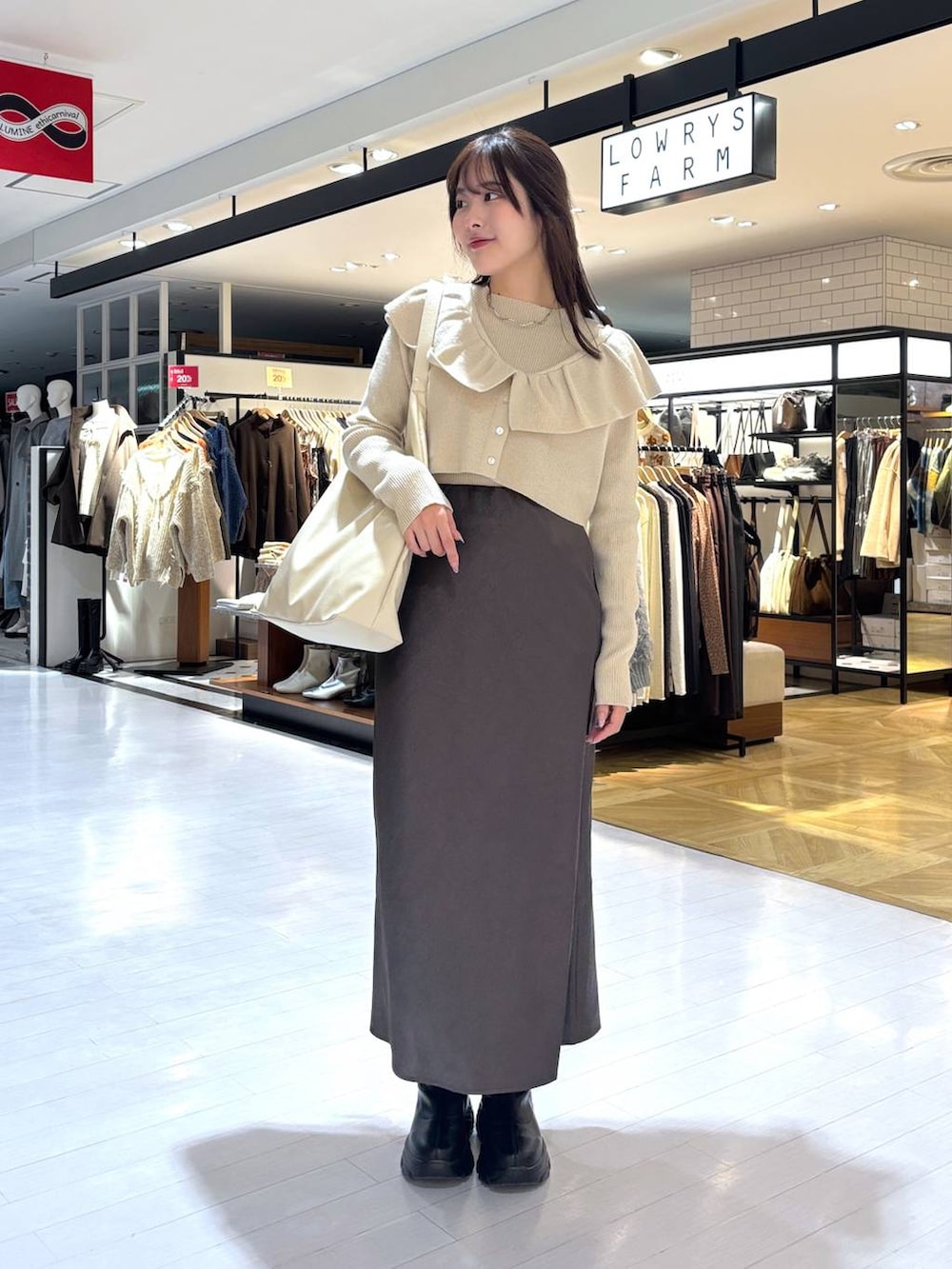 ホワイト系のショルダーバッグ、ベージュ系のニット/セーター、ブラック系のブーツを着用したレディースの冬コーディネートの4枚目の写真