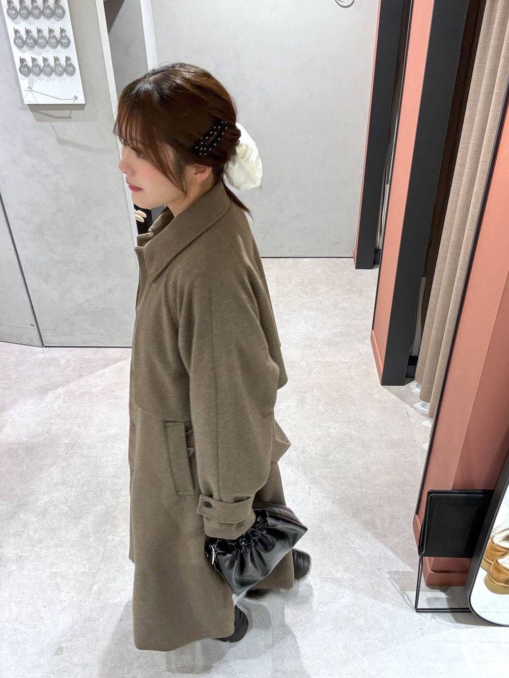 グレー系のスカート、ブラウン系のステンカラーコート、ブラック系のショルダーバッグを着用したレディースの冬コーディネートの2枚目の写真