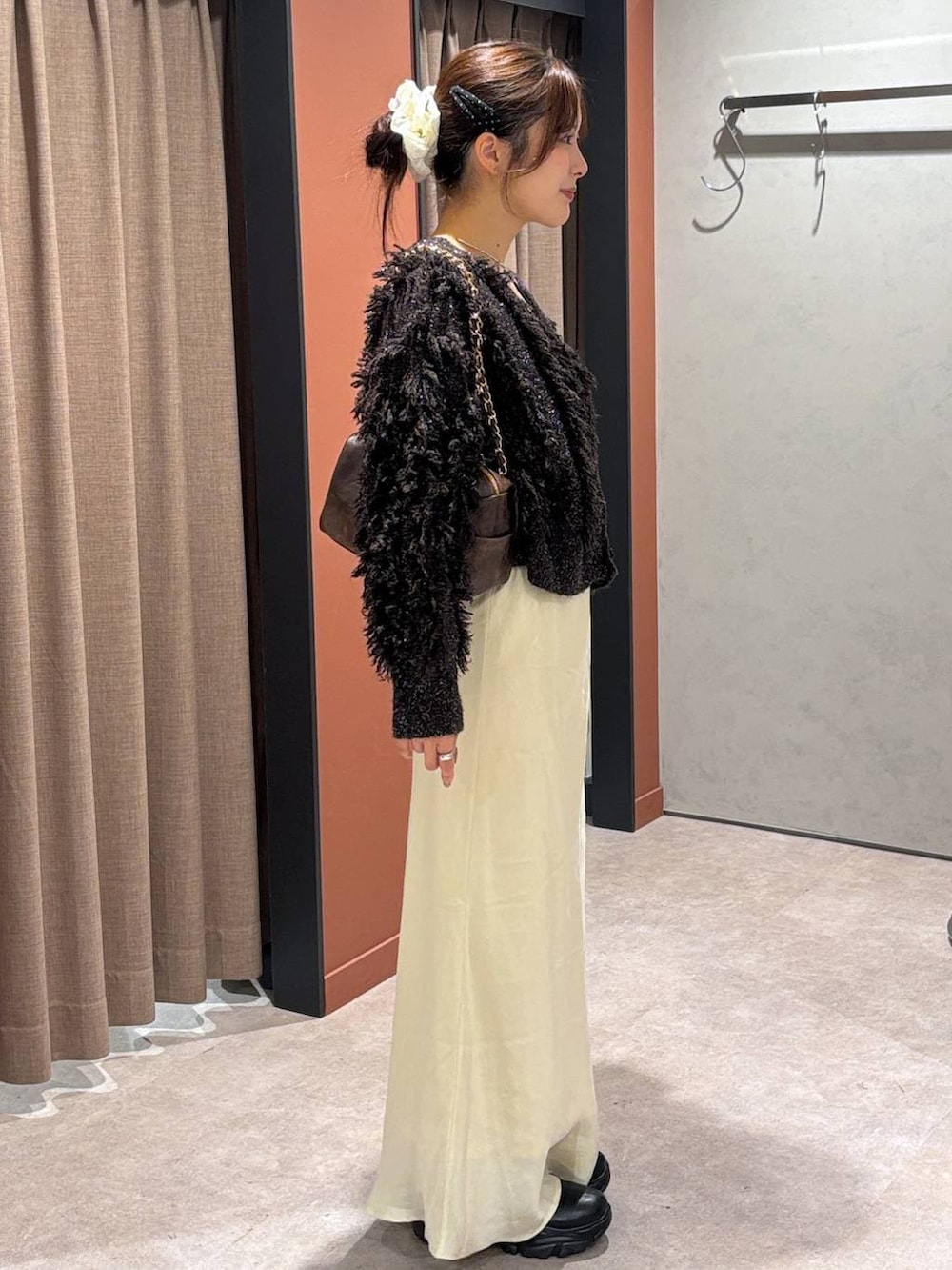 ブラック系のブーツ、ホワイト系のスカート、ブラウン系のカーディガン/ボレロを着用したレディースの秋コーディネートの2枚目の写真