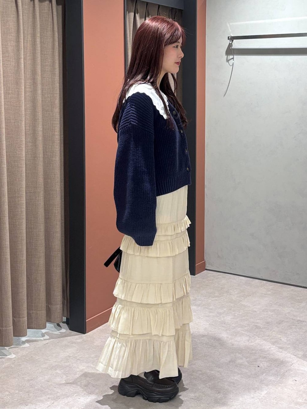 ブラック系のショルダーバッグ、ブラウン系のローファー、ホワイト系のスカートを着用したレディースの冬コーディネートの2枚目の写真