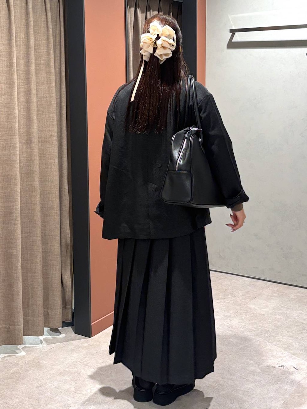 グレー系のテーラードジャケット、グレー系のスカート、ブラック系のボストンバッグを着用したレディースの秋コーディネートの3枚目の写真