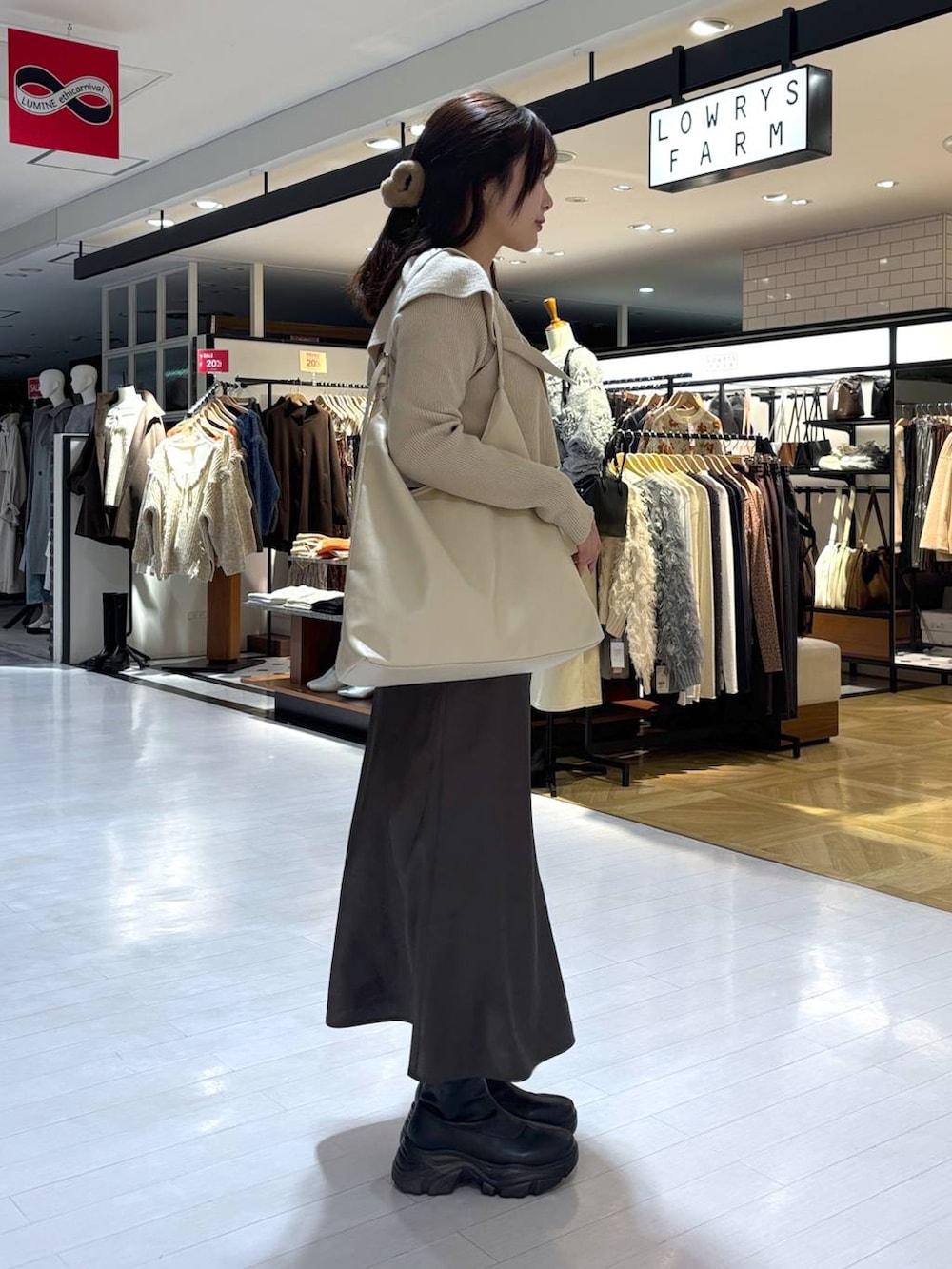 ホワイト系のショルダーバッグ、ベージュ系のニット/セーター、ブラック系のブーツを着用したレディースの冬コーディネートの2枚目の写真