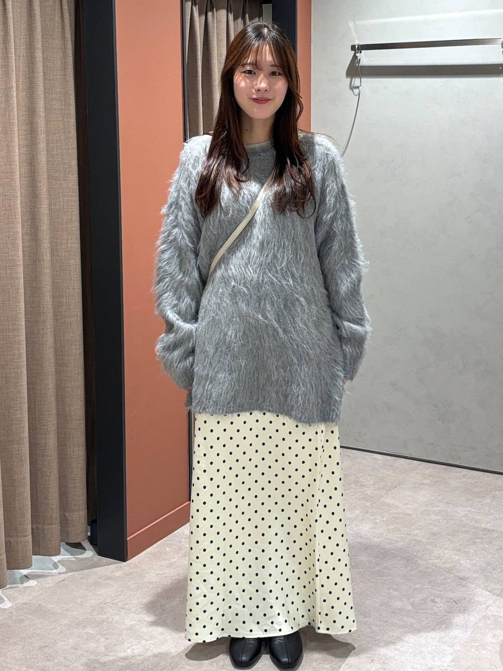 ホワイト系のスカート、ホワイト系のボストンバッグ、ブラック系のブーツを着用したレディースの冬コーディネートの4枚目の写真