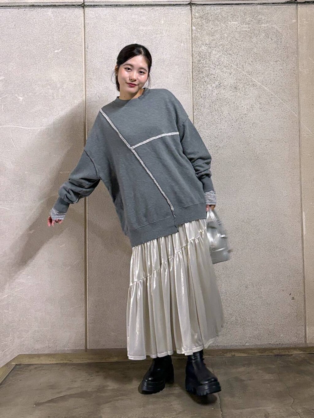 ブラック系のブーツ、ホワイト系のスカート、シルバー系のTシャツ/カットソーを着用したレディースの秋コーディネートの3枚目の写真