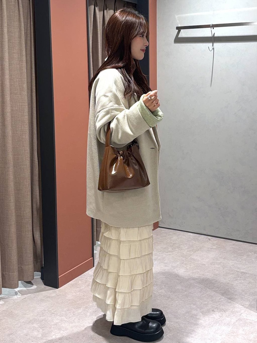 ホワイト系のその他アウター、ホワイト系のスカート、ブラック系のサンダルを着用したレディースの冬コーディネートの2枚目の写真