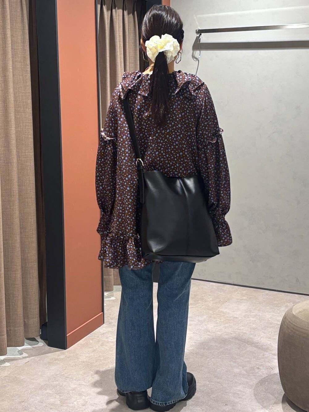 ブラック系のスニーカー、ブルー系のデニムパンツ、ブラック系のショルダーバッグを着用したレディースの秋コーディネートの3枚目の写真