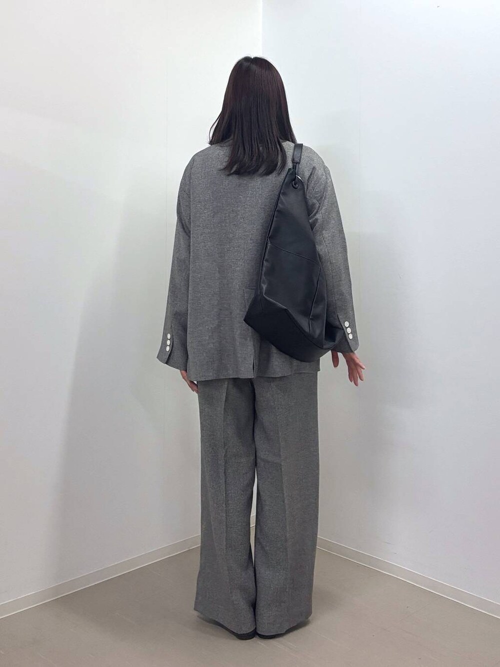 グレー系のスラックス、グレー系のテーラードジャケット、ブラック系のトートバッグを着用したレディースの春コーディネートの3枚目の写真