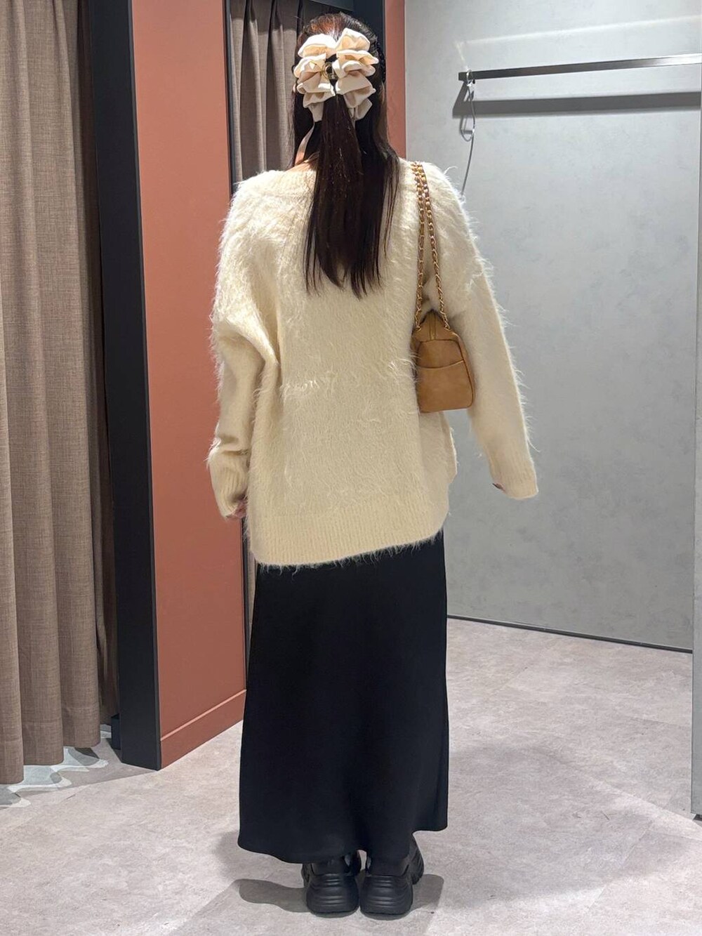 ブラック系のブーツ、ブラック系のスカート、ホワイト系のカーディガン/ボレロを着用したレディースの秋コーディネートの3枚目の写真