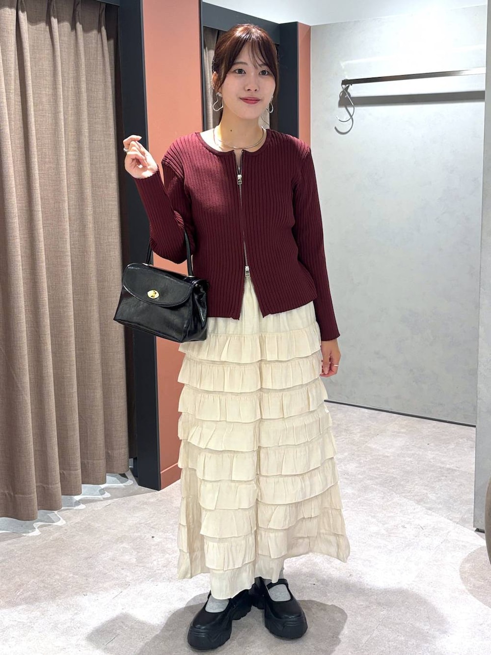 ブラック系のスニーカー、ブラック系のボストンバッグ、ホワイト系のスカートを着用したレディースの秋コーディネートの4枚目の写真