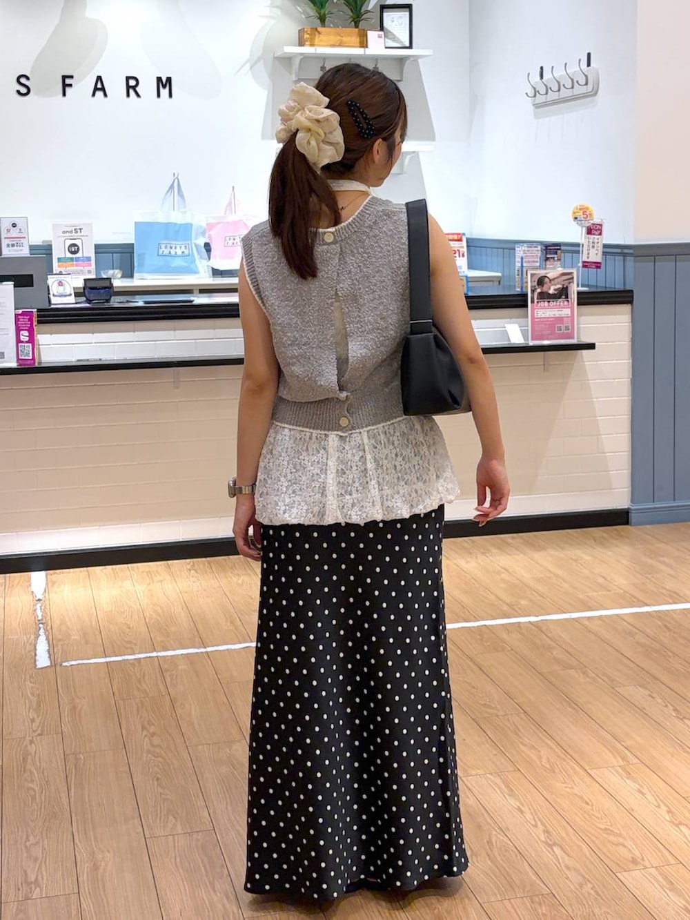 ブラック系のスカート、ブラック系のサンダル、グレー系のベストを着用したレディースの夏コーディネートの3枚目の写真