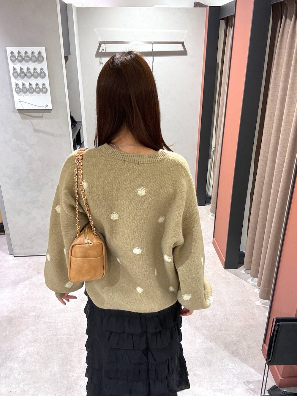 ブラック系のスカート、ベージュ系のショルダーバッグ、ゴールド系のニット/セーターを着用したレディースの冬コーディネートの3枚目の写真