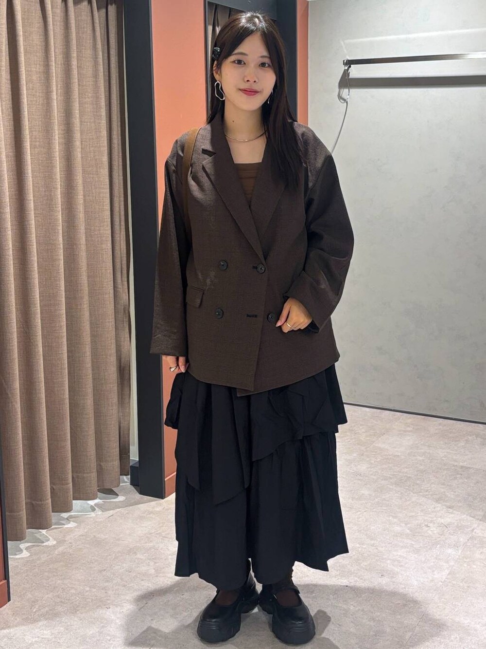 ブラック系のスニーカー、ブラウン系のテーラードジャケット、ブラウン系のショルダーバッグを着用したレディースの秋コーディネートの4枚目の写真