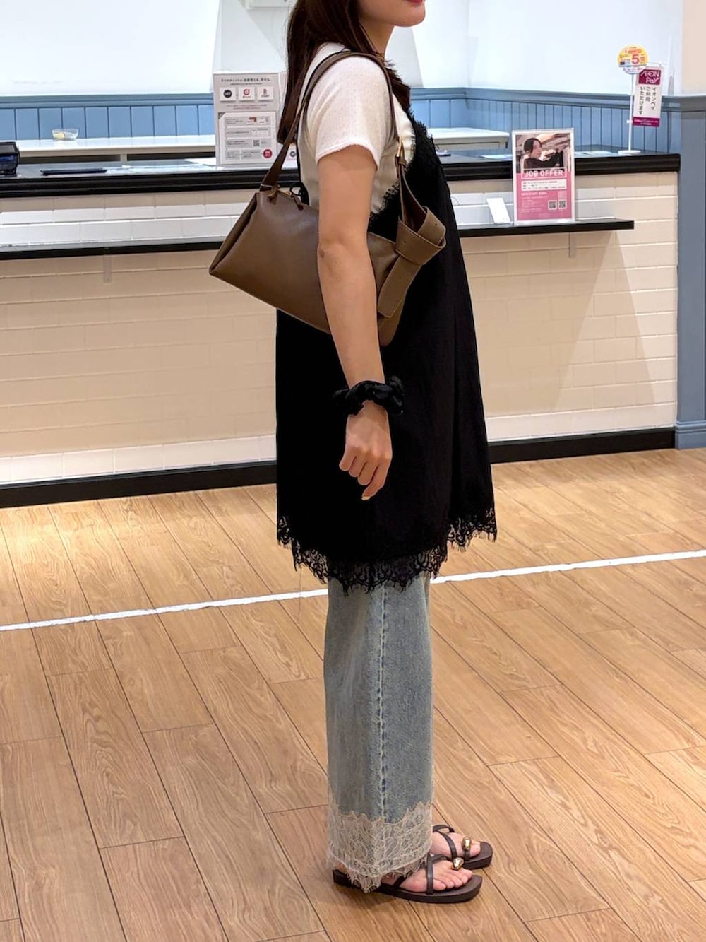 ブルー系のデニムパンツ、ブラウン系のサンダル、ブラウン系のショルダーバッグを着用したレディースの夏コーディネートの2枚目の写真