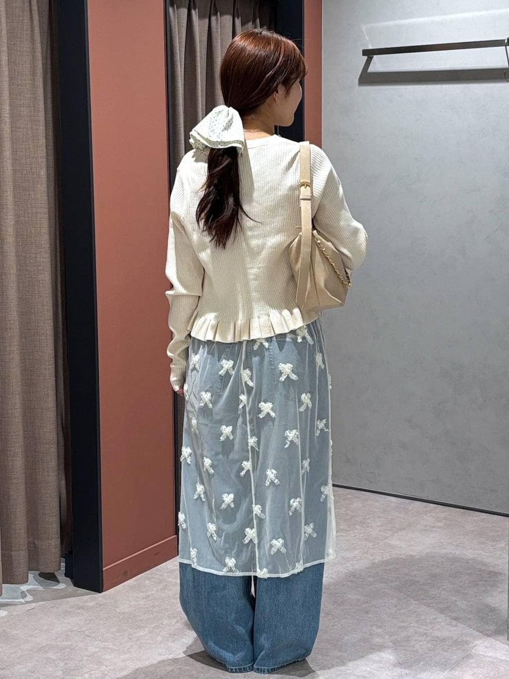 ブルー系のデニムパンツ、ベージュ系のショルダーバッグ、ブラック系のローファーを着用したレディースの春コーディネートの3枚目の写真