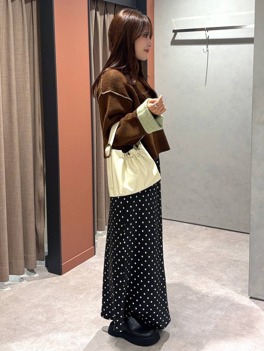 ブラック系のスカート、ブラック系のサンダル、ホワイト系のショルダーバッグを着用したレディースの冬コーディネートの2枚目の写真