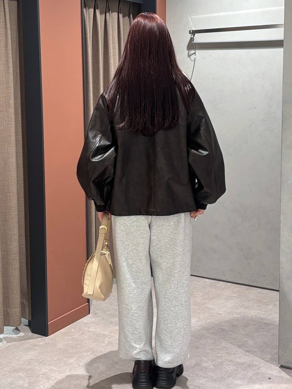 グレー系のスウェットパンツ、ベージュ系のショルダーバッグ、ブラック系のローファーを着用したレディースの冬コーディネートの3枚目の写真