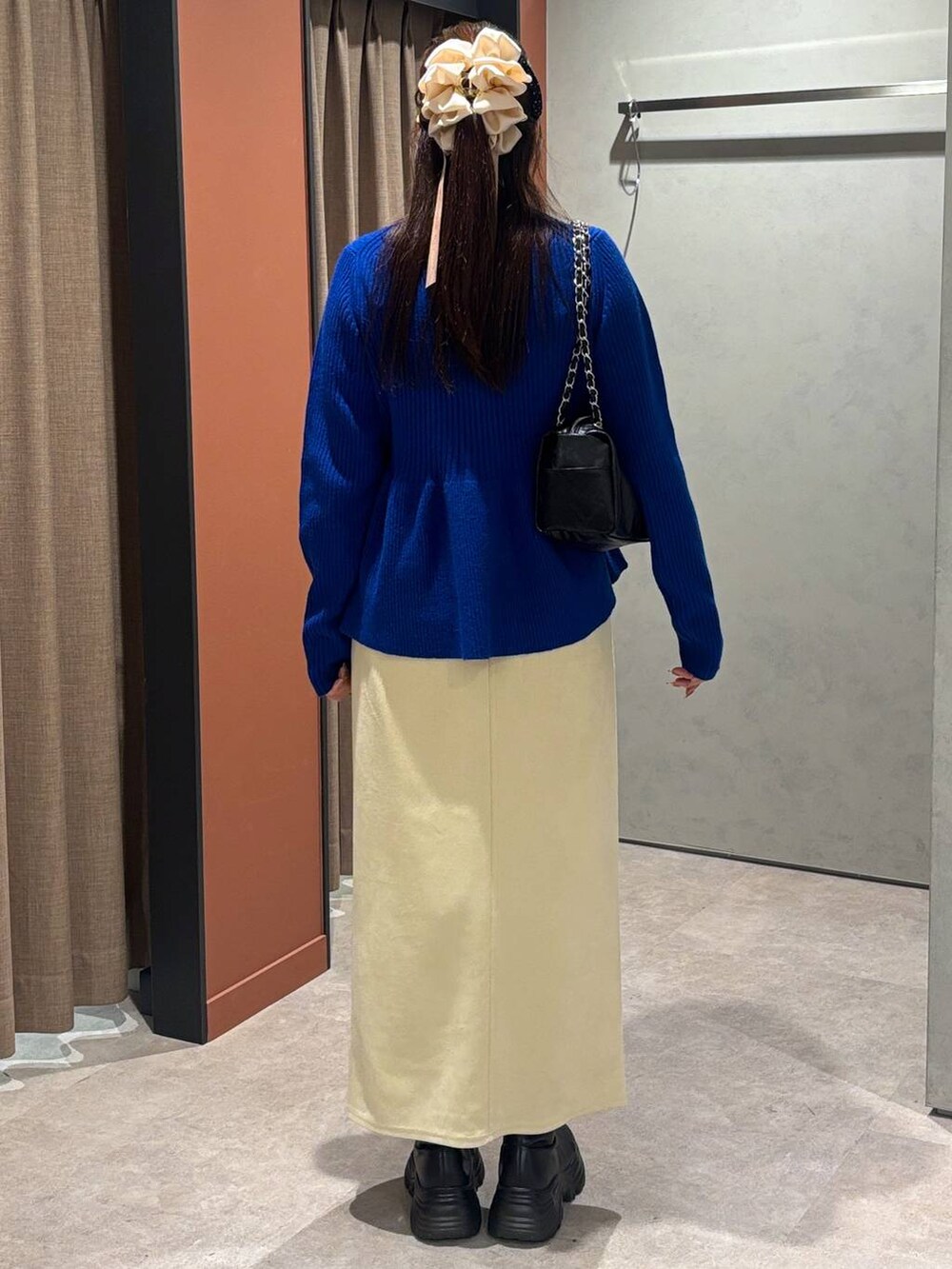 ブラック系のブーツ、ホワイト系のスカート、ブルー系のカーディガン/ボレロを着用したレディースの秋コーディネートの3枚目の写真