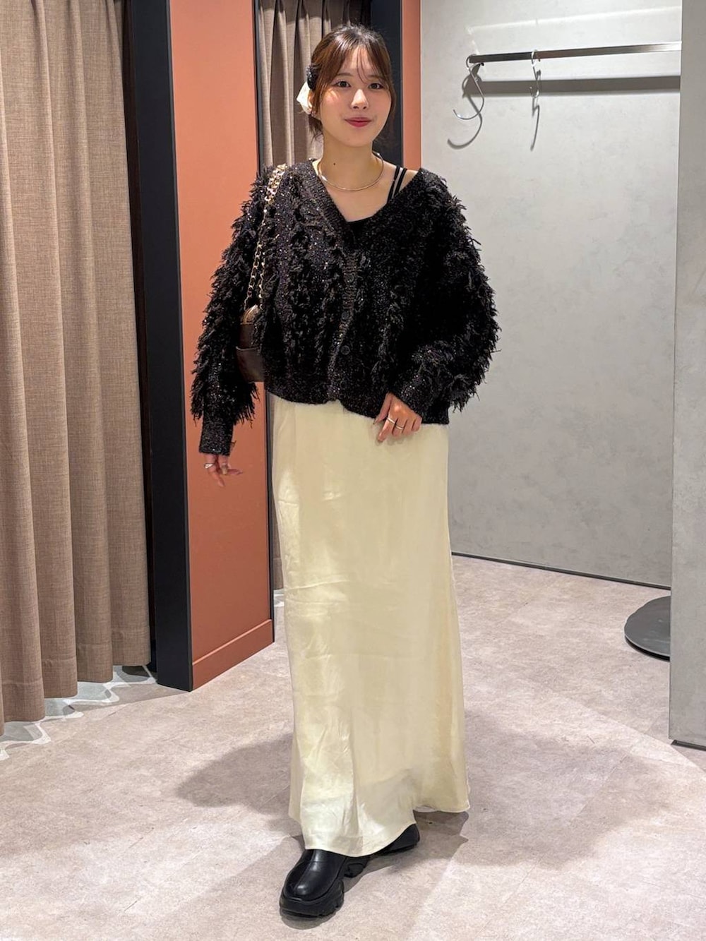 ブラック系のブーツ、ホワイト系のスカート、ブラウン系のカーディガン/ボレロを着用したレディースの秋コーディネートの4枚目の写真