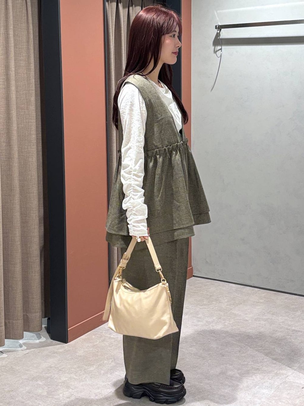 ブラウン系のデニムパンツ、ブラウン系のベスト、ホワイト系のTシャツ/カットソーを着用したレディースの冬コーディネートの2枚目の写真