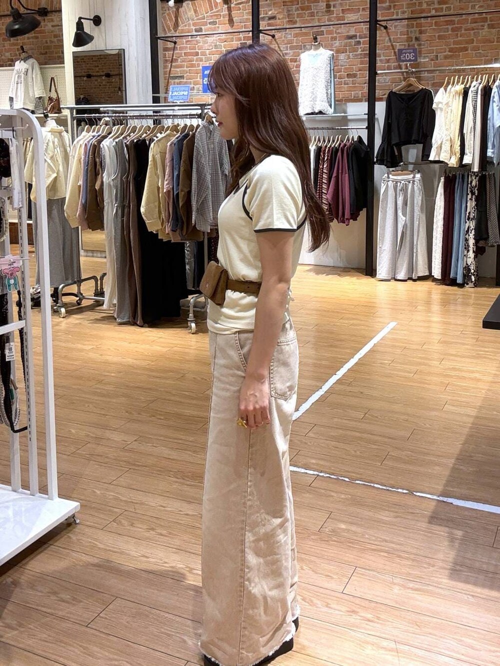 オレンジ系のデニムパンツ、ブラック系のサンダル、イエロー系のベルトを着用したレディースの春コーディネートの3枚目の写真