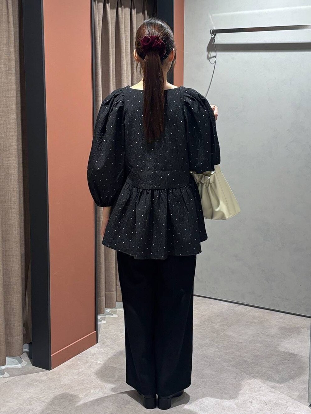 ブラック系のブーツ、ホワイト系のショルダーバッグ、ブラック系のスラックスを着用したレディースの冬コーディネートの3枚目の写真