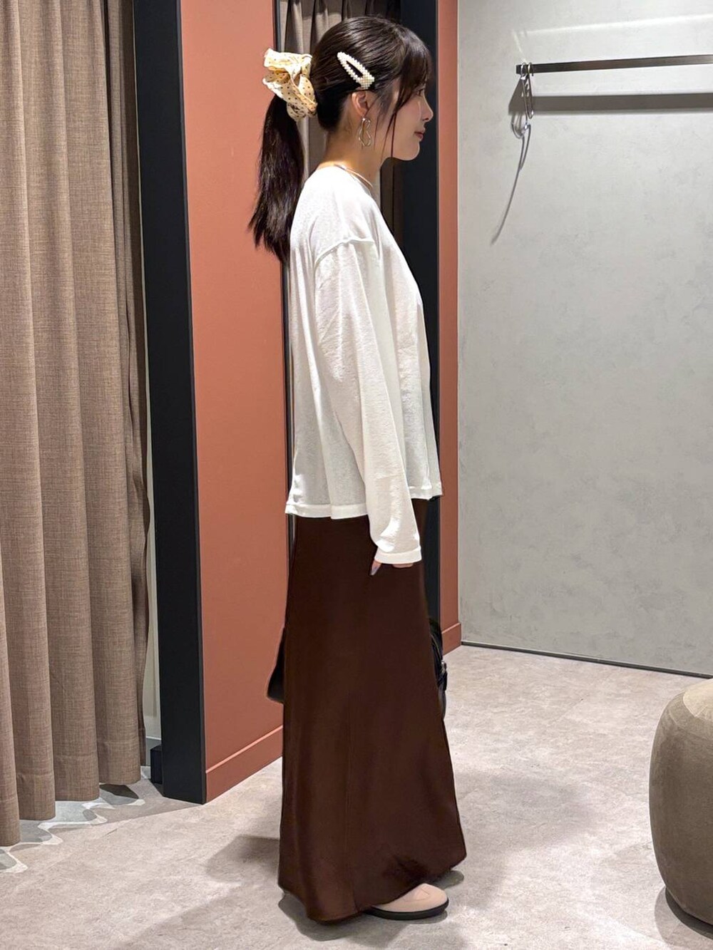 ブラウン系のスカート、ピンク系のスニーカー、ブラック系のボストンバッグを着用したレディースの秋コーディネートの3枚目の写真