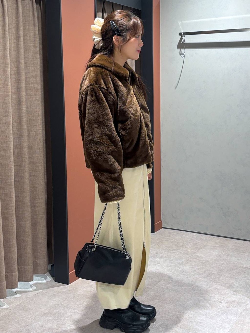 ブラック系のブーツ、ブラウン系のブルゾン、ホワイト系のスカートを着用したレディースの冬コーディネートの2枚目の写真