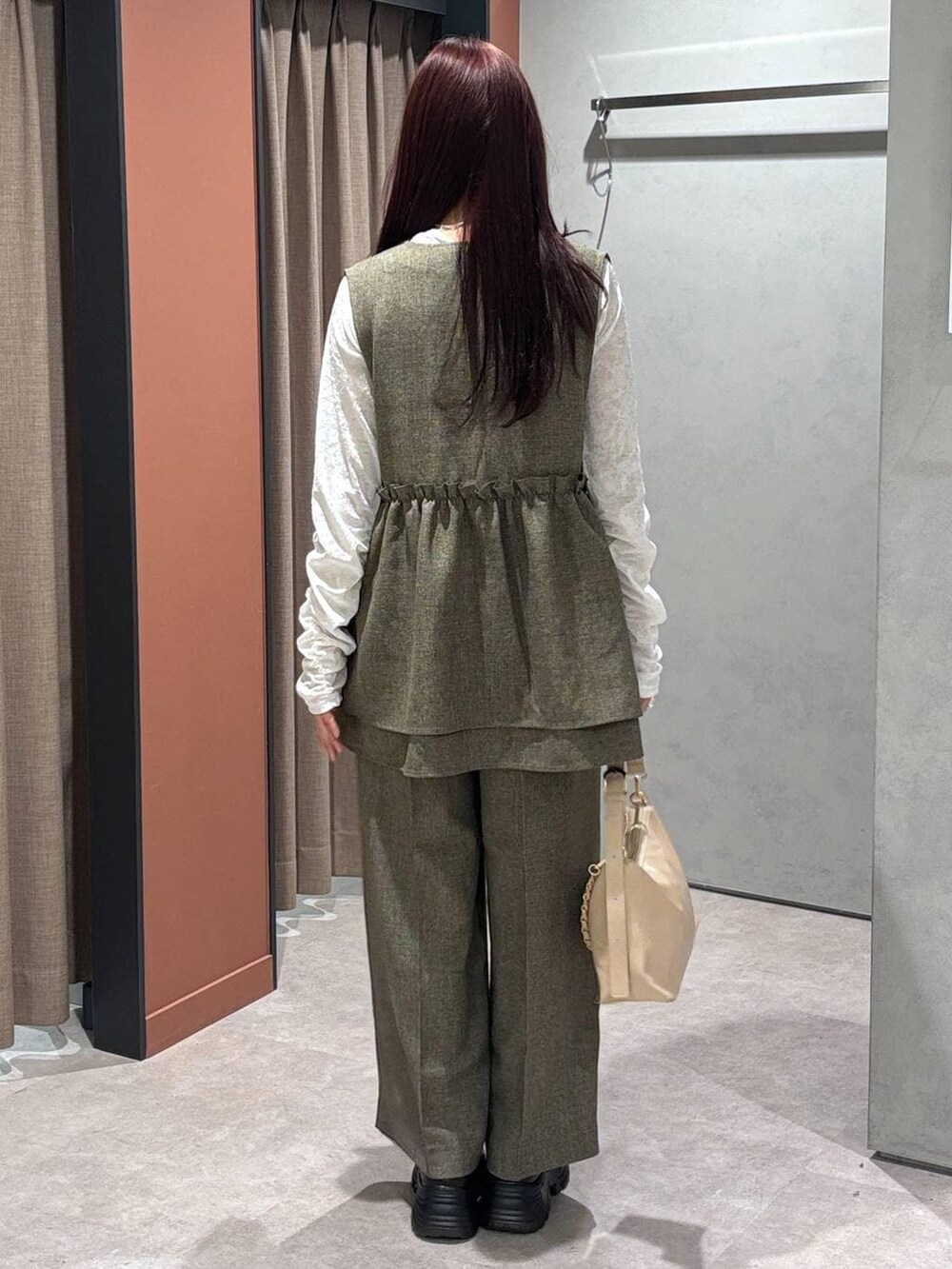 ブラウン系のデニムパンツ、ブラウン系のベスト、ホワイト系のTシャツ/カットソーを着用したレディースの冬コーディネートの3枚目の写真