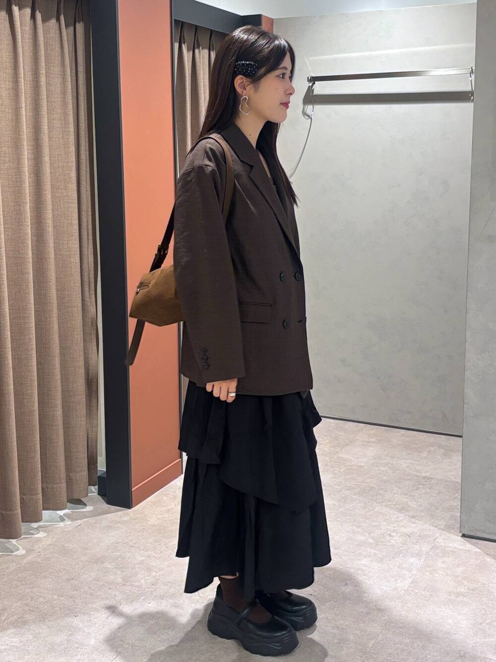 ブラック系のスニーカー、ブラウン系のテーラードジャケット、ブラウン系のショルダーバッグを着用したレディースの秋コーディネートの2枚目の写真
