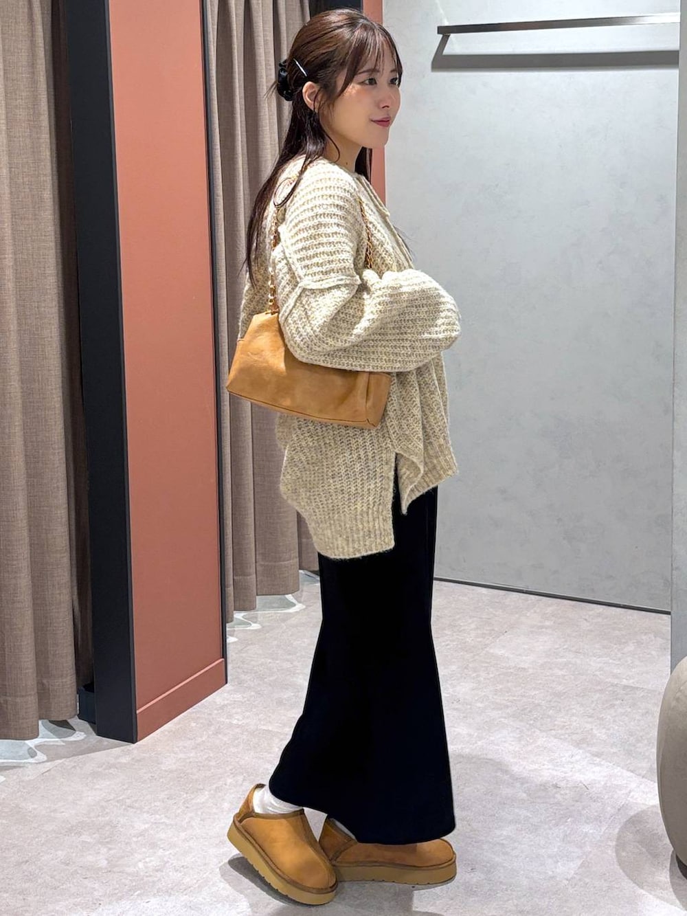 ブラック系のスカート、ホワイト系のニット/セーター、ベージュ系のショルダーバッグを着用したレディースの秋コーディネートの2枚目の写真