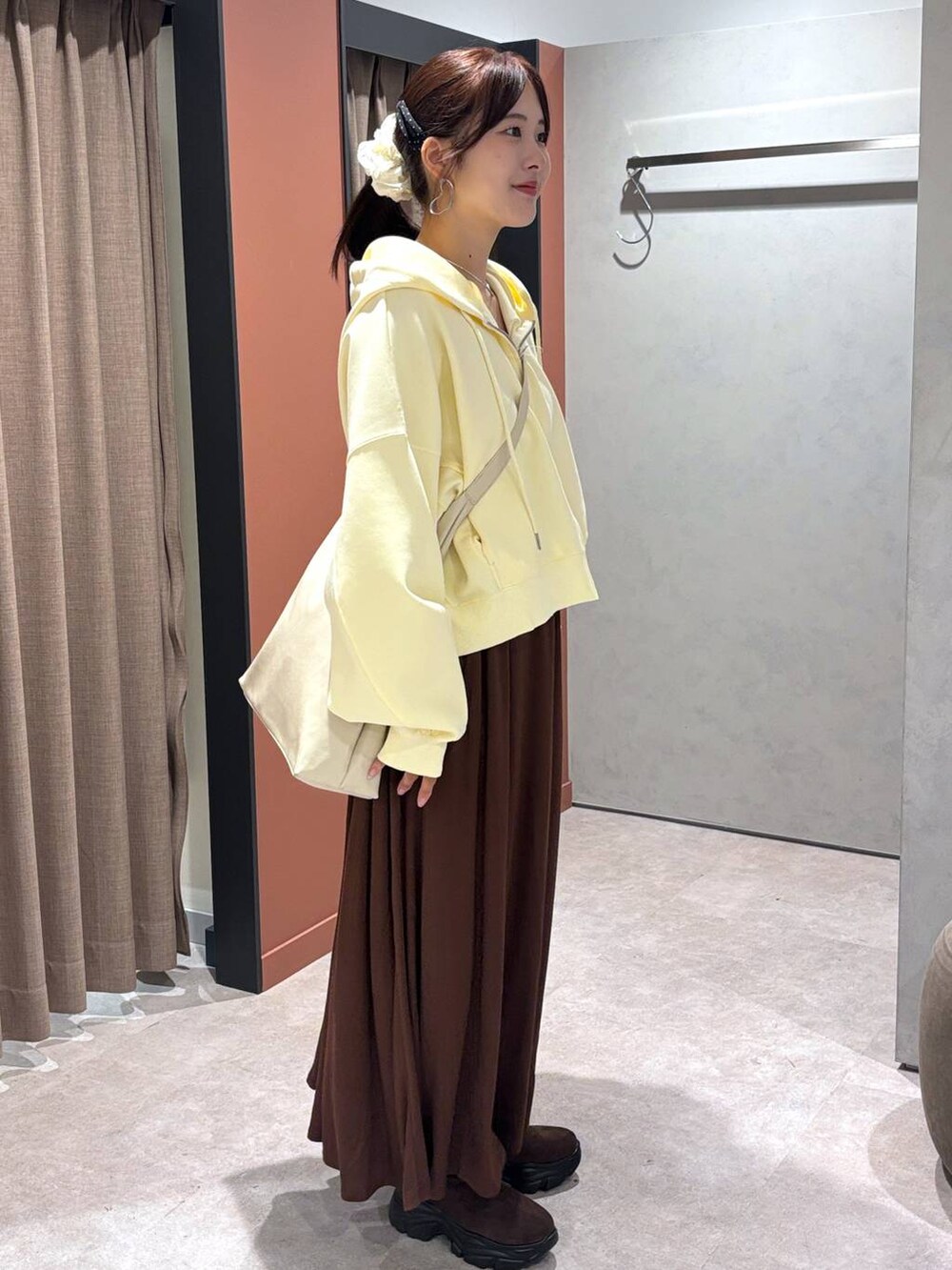 ホワイト系のショルダーバッグ、ブラウン系のスカート、イエロー系のパーカーを着用したレディースの秋コーディネートの2枚目の写真