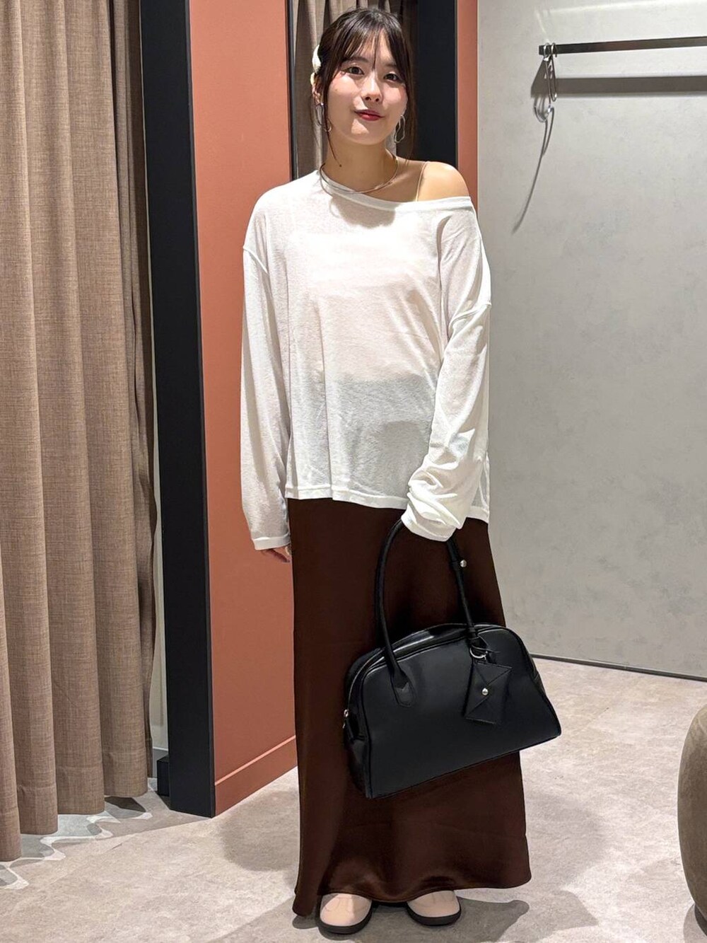 ブラウン系のスカート、ピンク系のスニーカー、ブラック系のボストンバッグを着用したレディースの秋コーディネートの4枚目の写真