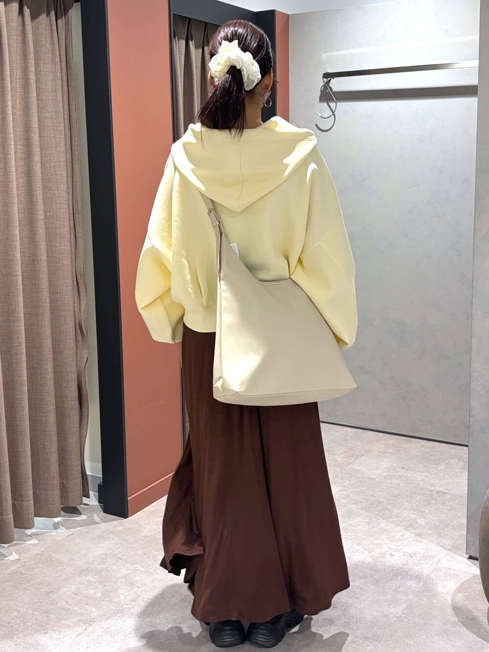 ホワイト系のショルダーバッグ、ブラウン系のスカート、イエロー系のパーカーを着用したレディースの秋コーディネートの3枚目の写真