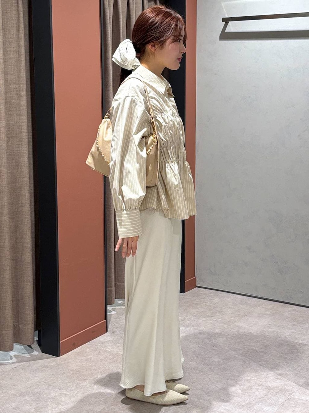 ホワイト系のスカート、ベージュ系のショルダーバッグ、ホワイト系のパンプスを着用したレディースの春コーディネートの2枚目の写真