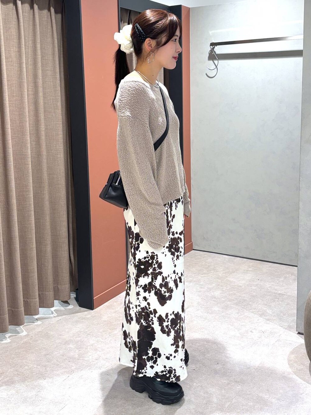 ブラック系のブーツ、その他のスカート、ブラック系のショルダーバッグを着用したレディースの秋コーディネートの2枚目の写真