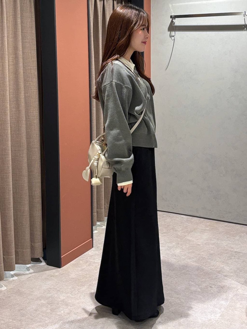 ブラック系のスカート、ホワイト系のボストンバッグ、ブラック系のブーツを着用したレディースの冬コーディネートの2枚目の写真