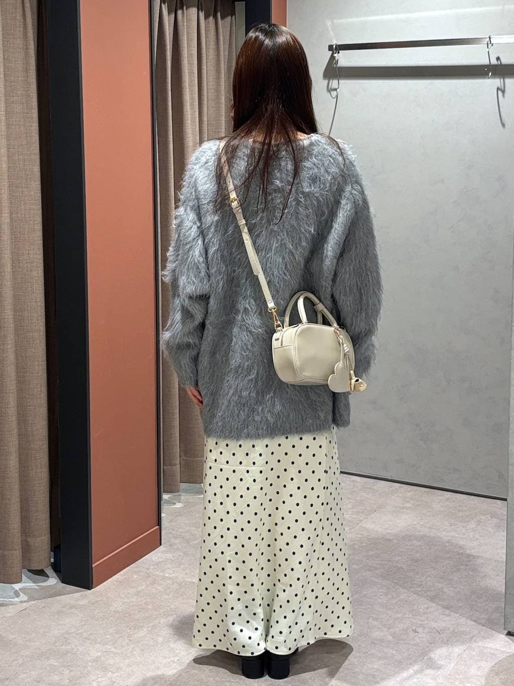 ホワイト系のスカート、ホワイト系のボストンバッグ、ブラック系のブーツを着用したレディースの冬コーディネートの3枚目の写真