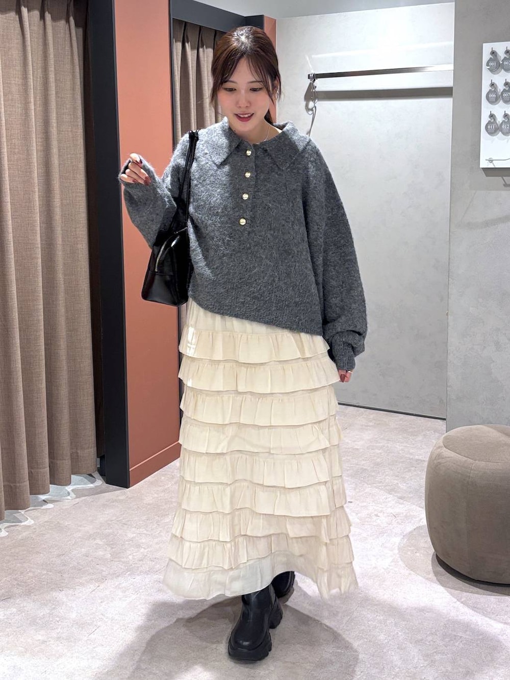 ブラック系のブーツ、ホワイト系のスカート、グレー系のニット/セーターを着用したレディースの秋コーディネートの4枚目の写真