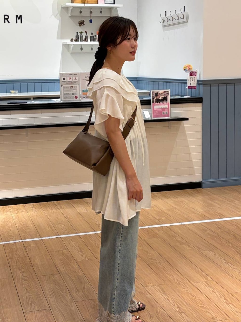 ブルー系のデニムパンツ、ブラウン系のサンダル、ブラウン系のショルダーバッグを着用したレディースの夏コーディネートの3枚目の写真