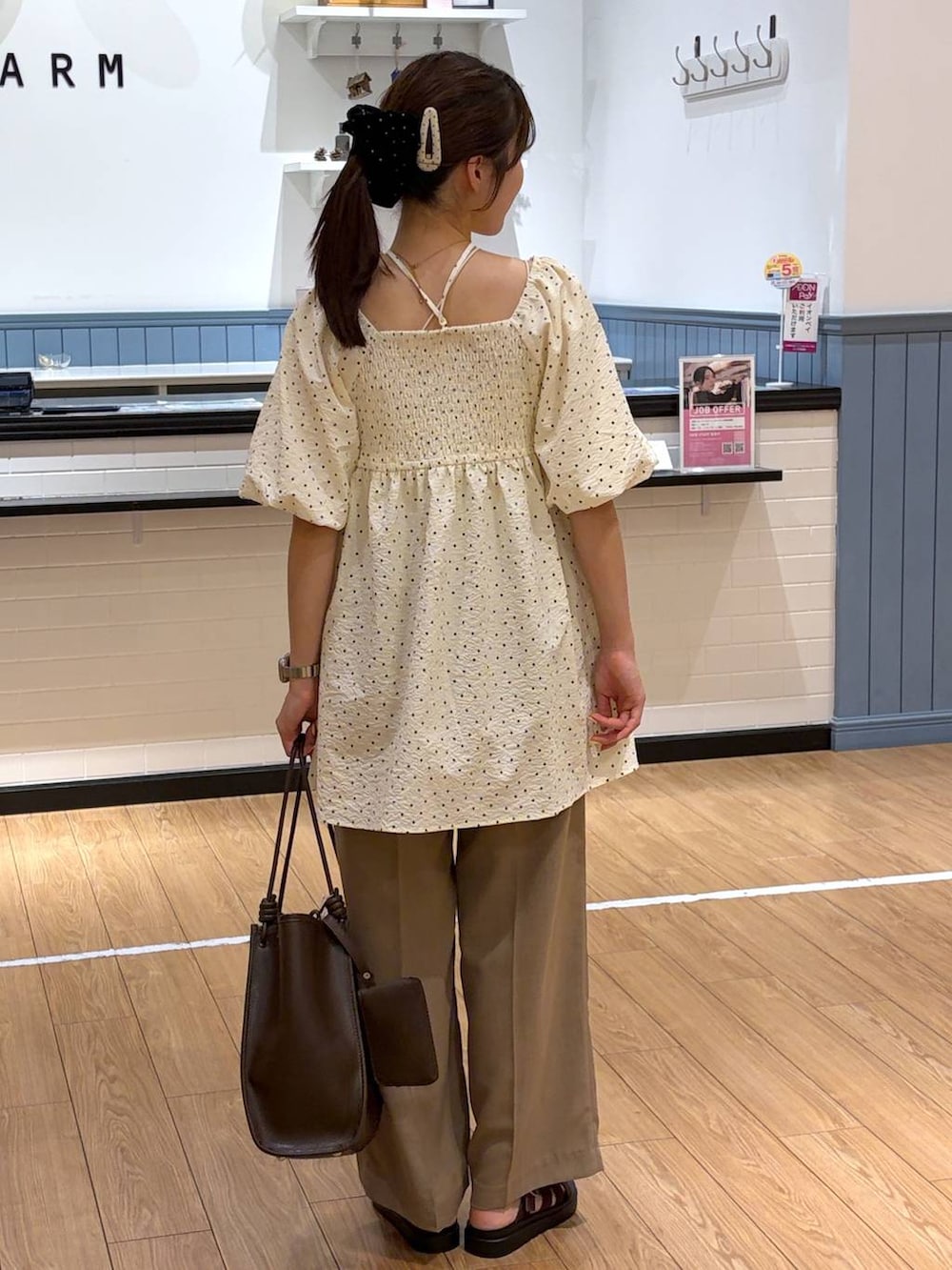 ベージュ系のスラックス、ブラウン系のサンダル、ブラウン系のトートバッグを着用したレディースの夏コーディネートの3枚目の写真
