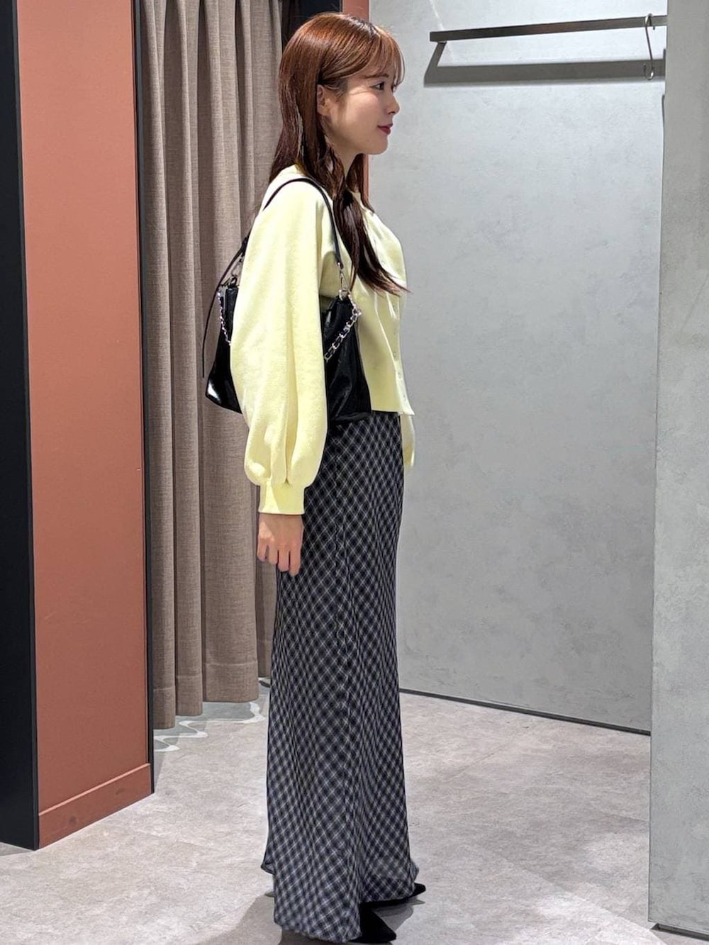 ブラック系のショルダーバッグ、ブラック系のパンプス、イエロー系のスウェットを着用したレディースの春コーディネートの2枚目の写真