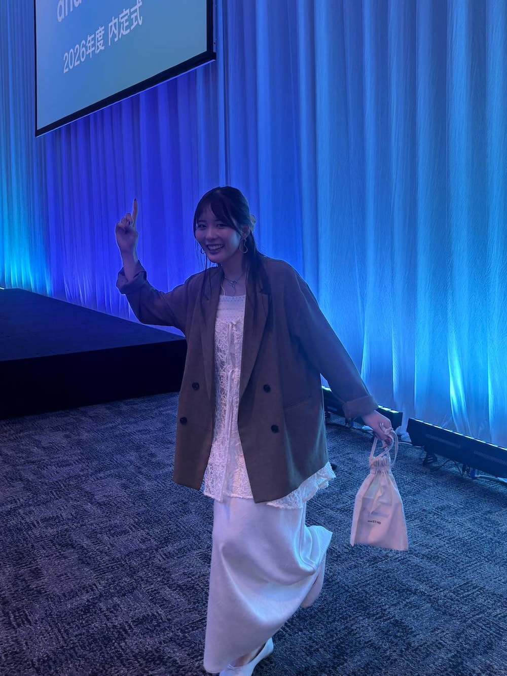 ホワイト系のスカート、ホワイト系のワンピース、ブラウン系のテーラードジャケットを着用したレディースの秋コーディネートの3枚目の写真