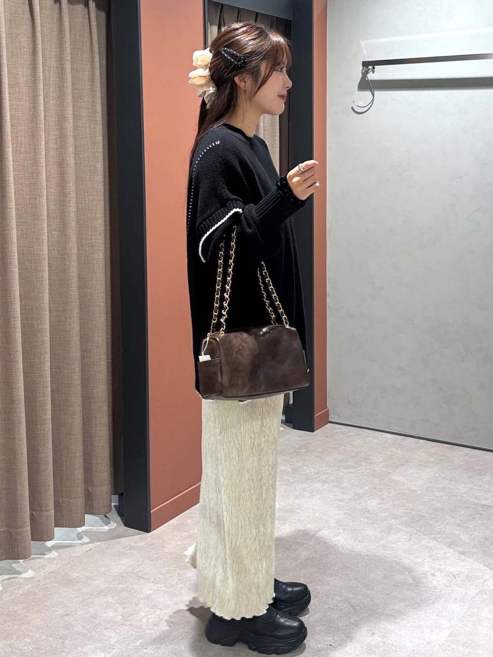 ブラック系のブーツ、ブラック系のニット/セーター、ホワイト系のスカートを着用したレディースの冬コーディネートの2枚目の写真