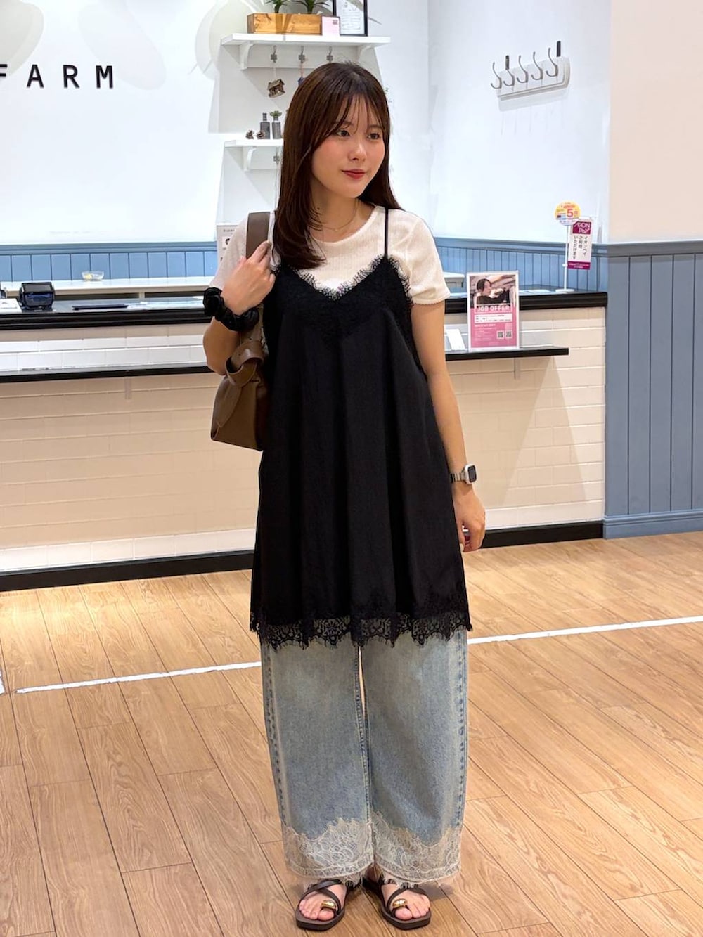 ブルー系のデニムパンツ、ブラウン系のサンダル、ブラウン系のショルダーバッグを着用したレディースの夏コーディネートの3枚目の写真
