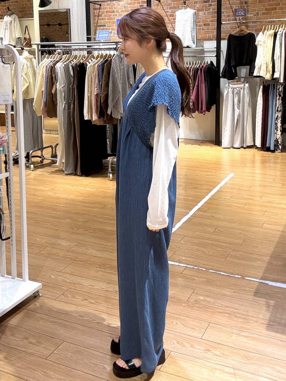 ブルー系のサロペット/オーバーオール、ホワイト系のTシャツ/カットソー、ブラック系のサンダルを着用したレディースの春コーディネートの3枚目の写真